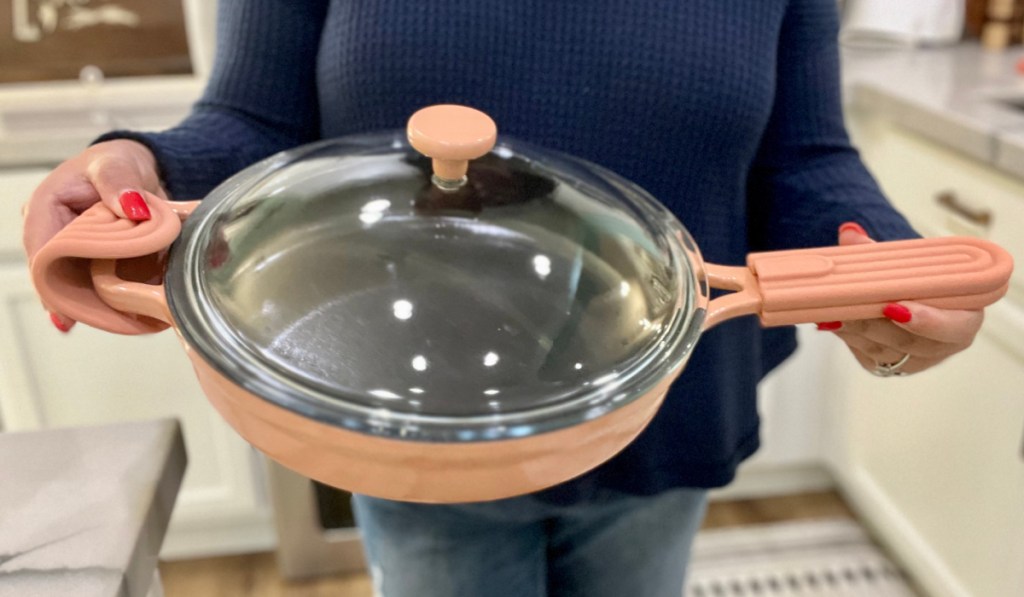 woman holding terra cotta cast iron pan with lid