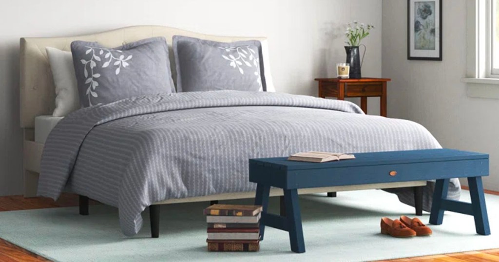 beige headboard with gray comforter set and blue bench in front of it