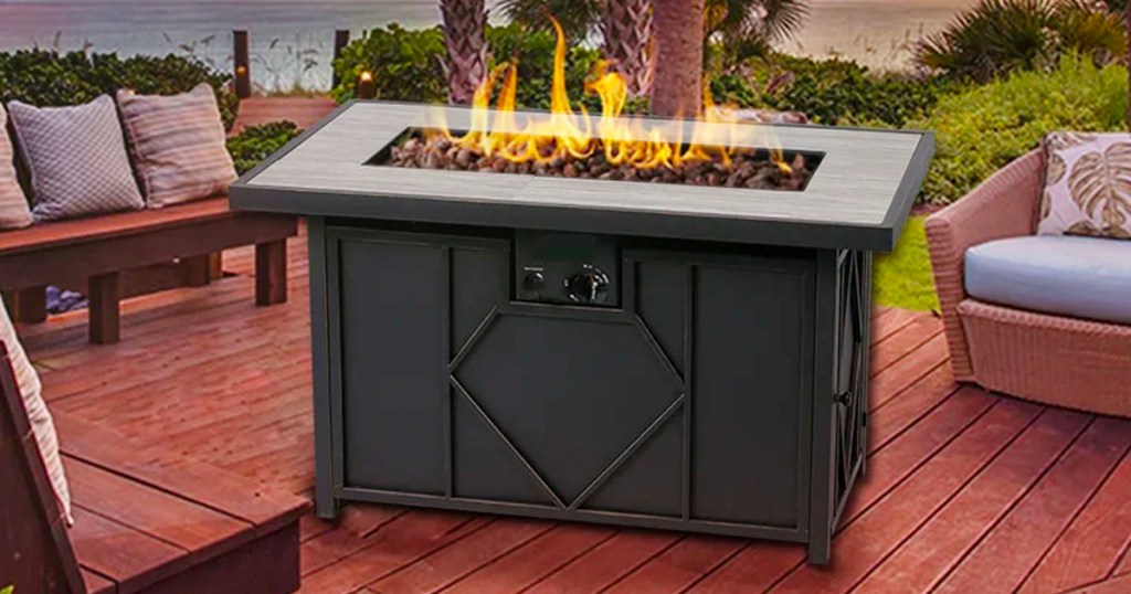 black firepit with fire on porch next to wooden patio furniture
