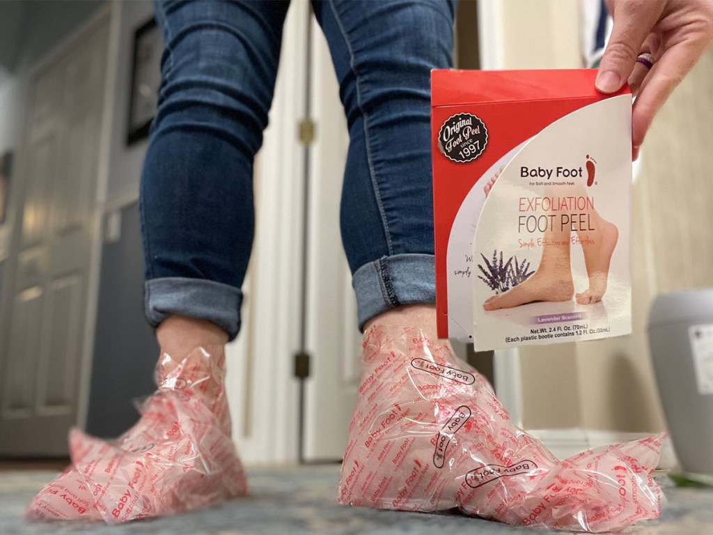 woman with foot mask booties on holding baby foot peel box