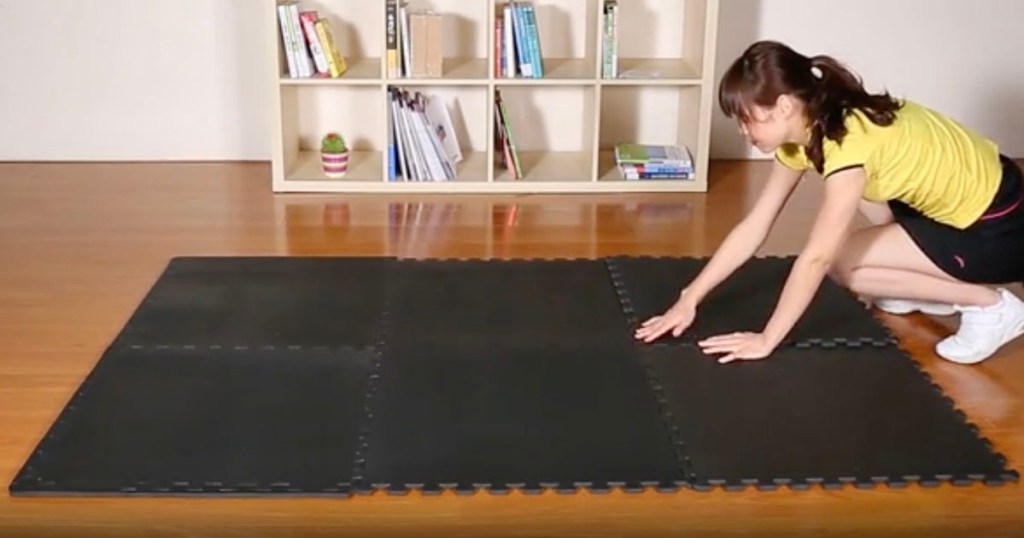woman putting down black interlocking foam mat on floor