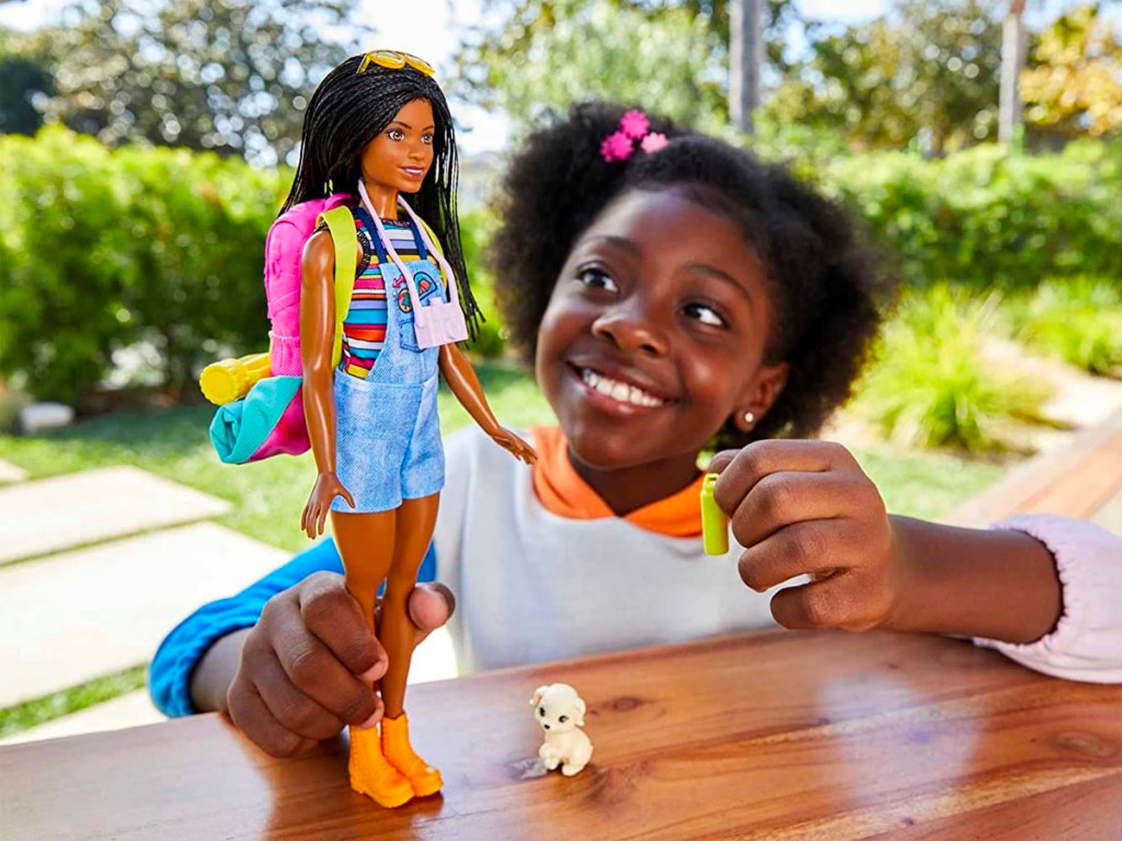 little girl playing with barbie doll with camping gear