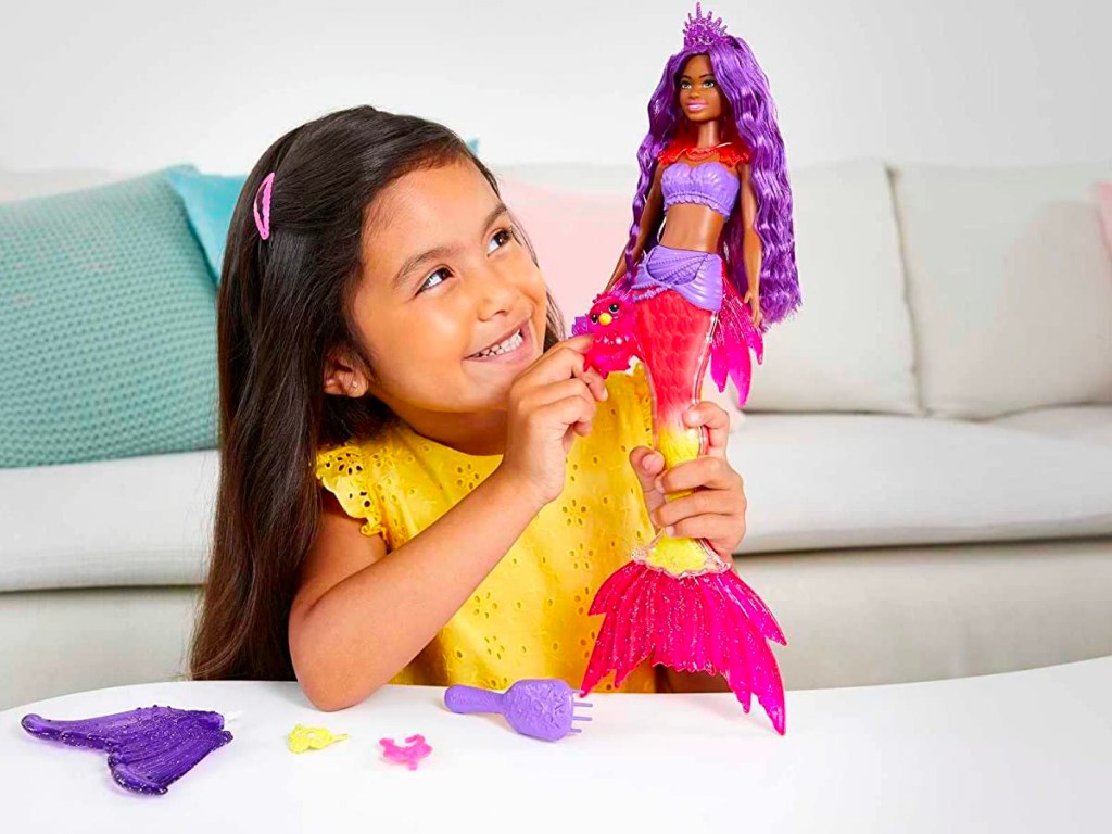 little girl playing with barbie mermaid doll 