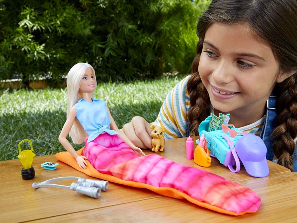 little girl playing with barbie doll with camping gear