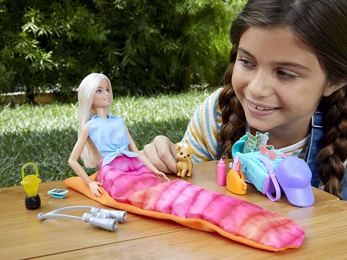 little girl playing with barbie doll with camping gear