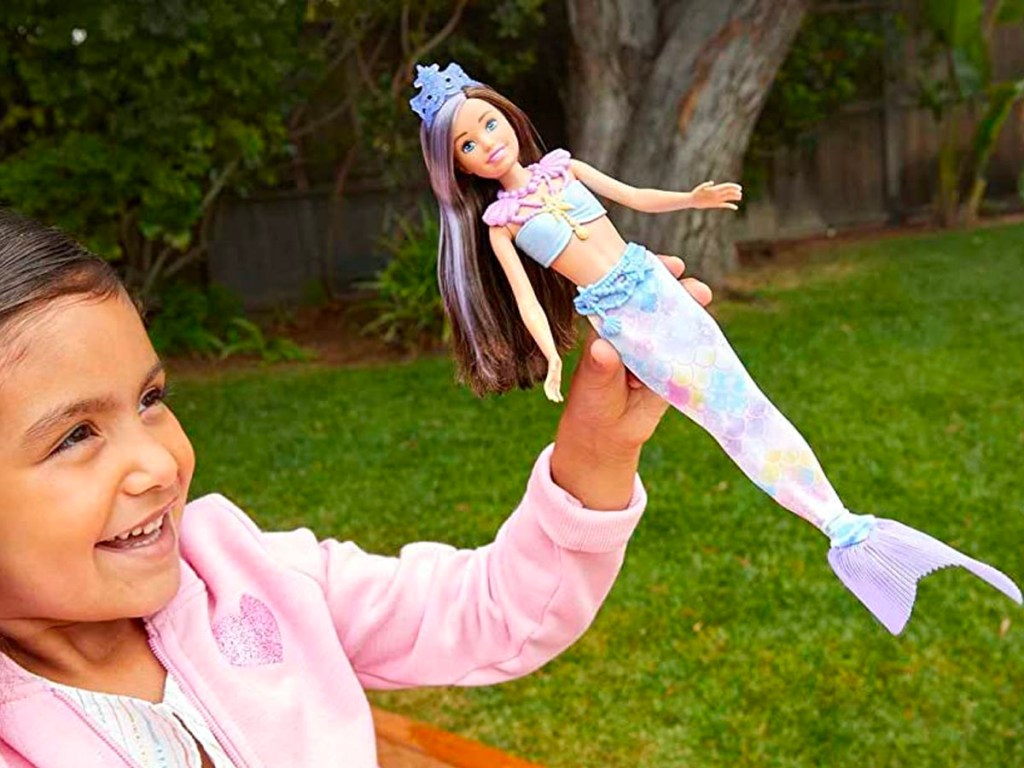 little girl playing with barbie mermaid doll 