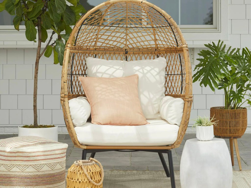 brown wicker egg chair with white cushions on porch