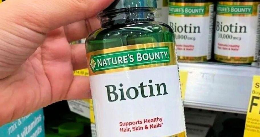 Hand holding a bottle of Nature's Bounty biotin
