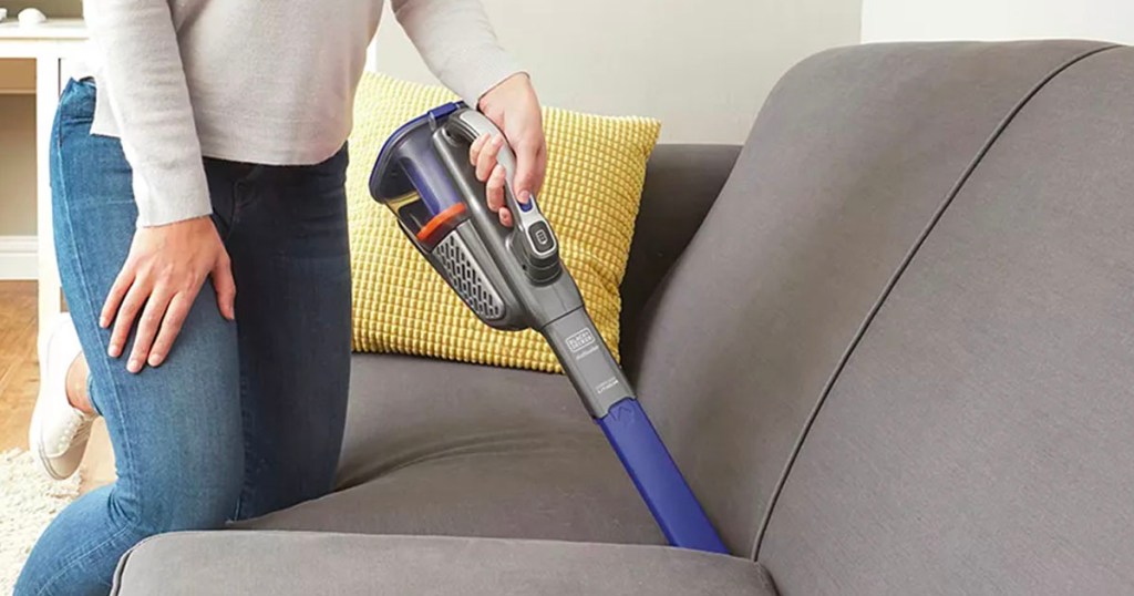 person using dustbuster to clean couch