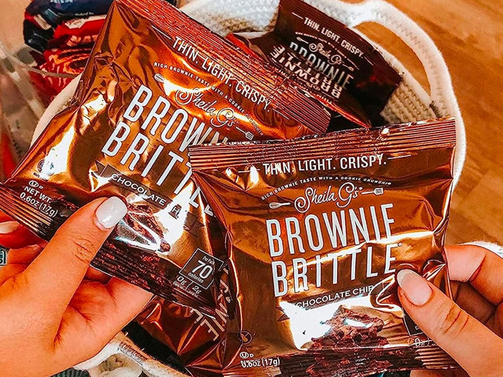 two hands holding bags of brownie brittle