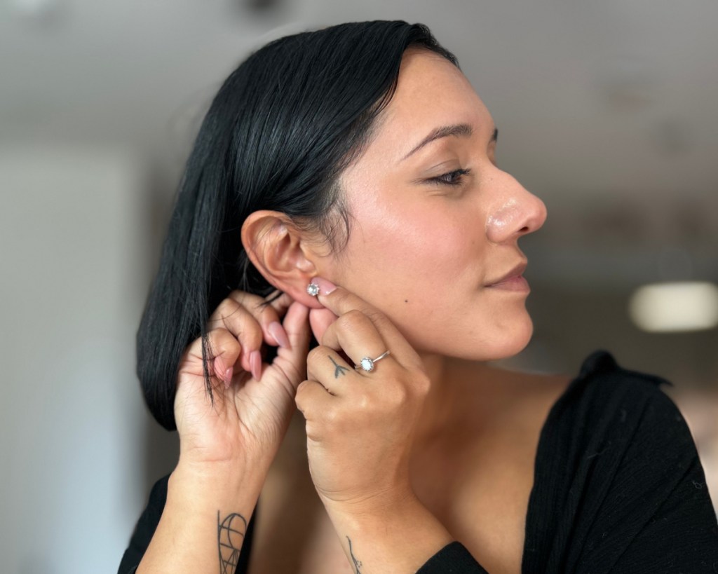 woman putting on stud earring