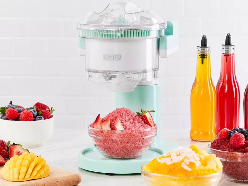 dash shaved ice maker next to fruit, shaved ice and syrups
