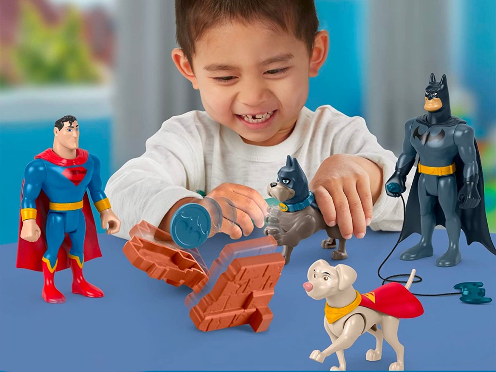 boy playing with DC action figures superman, batman and more