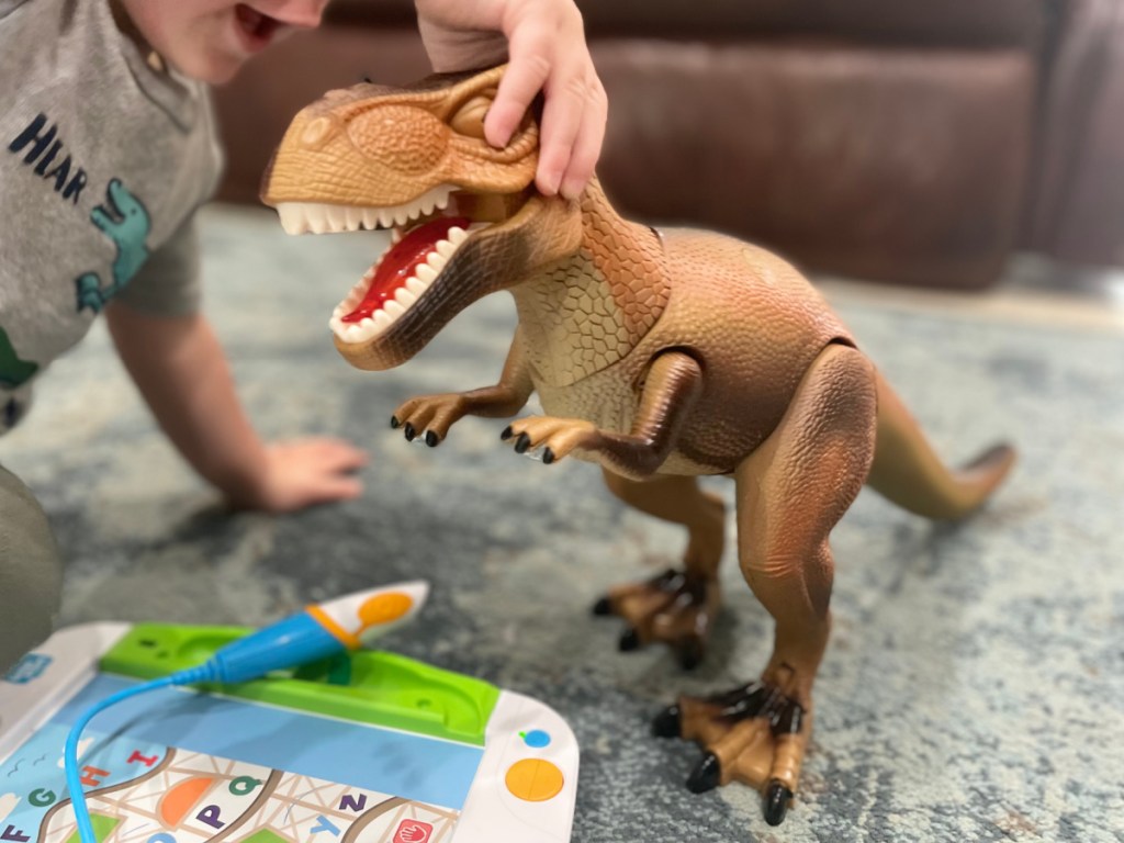 boy holding dino toy on the head