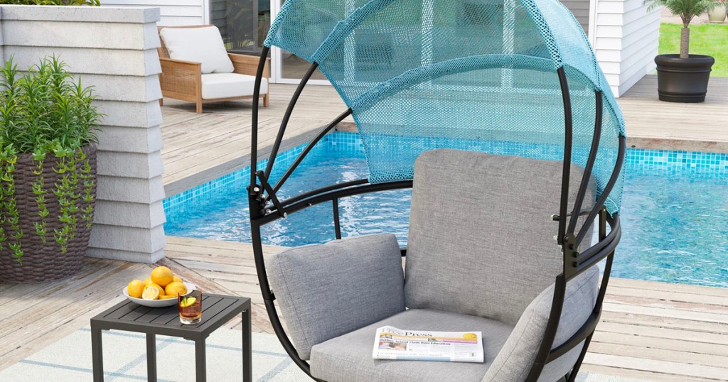 blue and gray egg chair with canopy up on pool deck