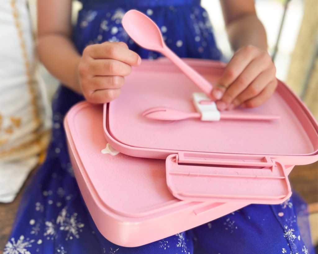 girl removing spoon from bento box