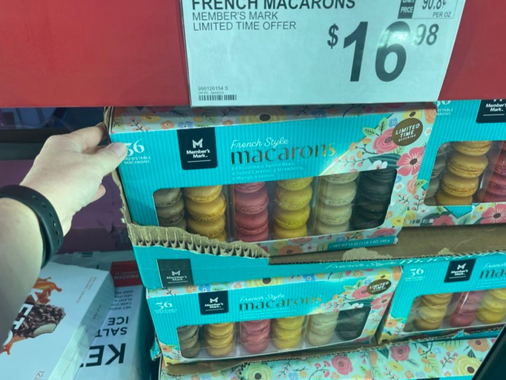 hand holding french macarons on shelf