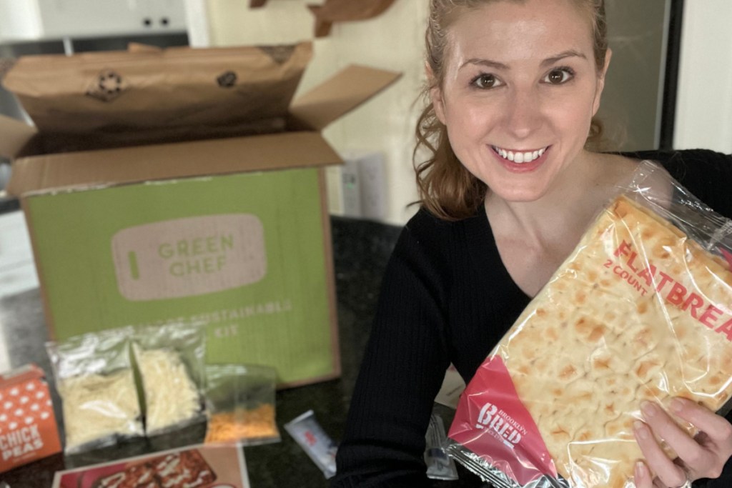 woman holding flatbread next to green chef box