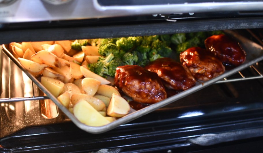 potatoes, chicken, and broccoli on pan in oven