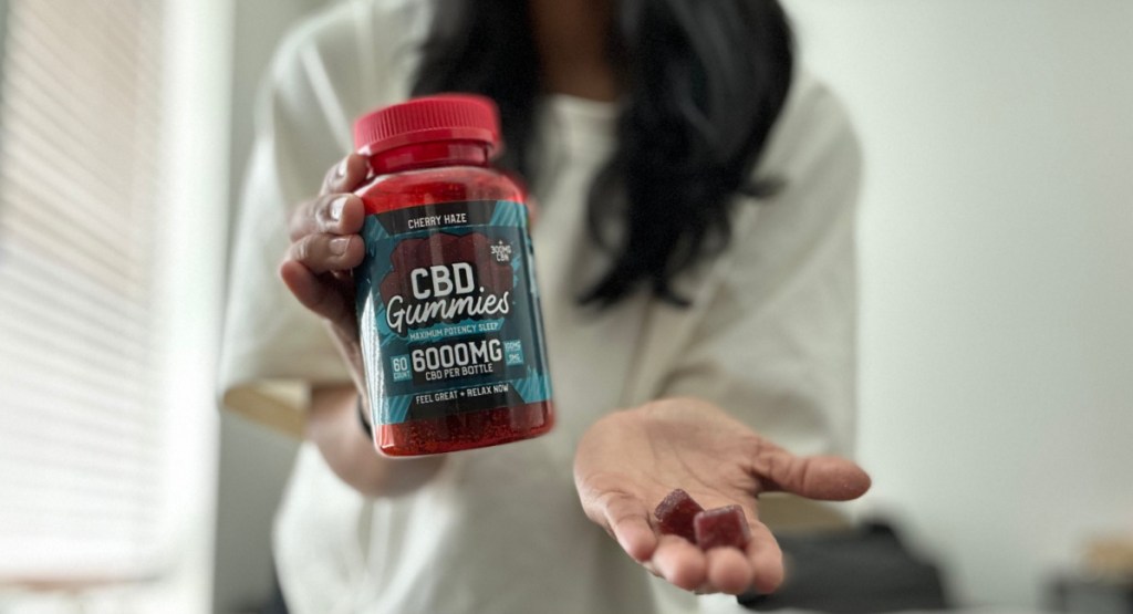 woman holding CBD gummies in hand and in jar