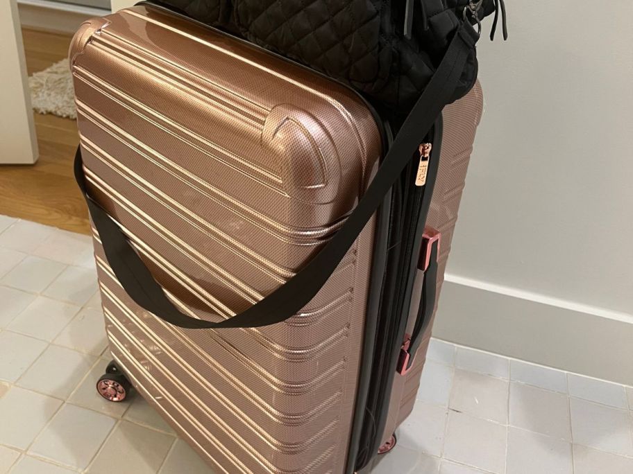 pink suitcase with a black bag sitting on top