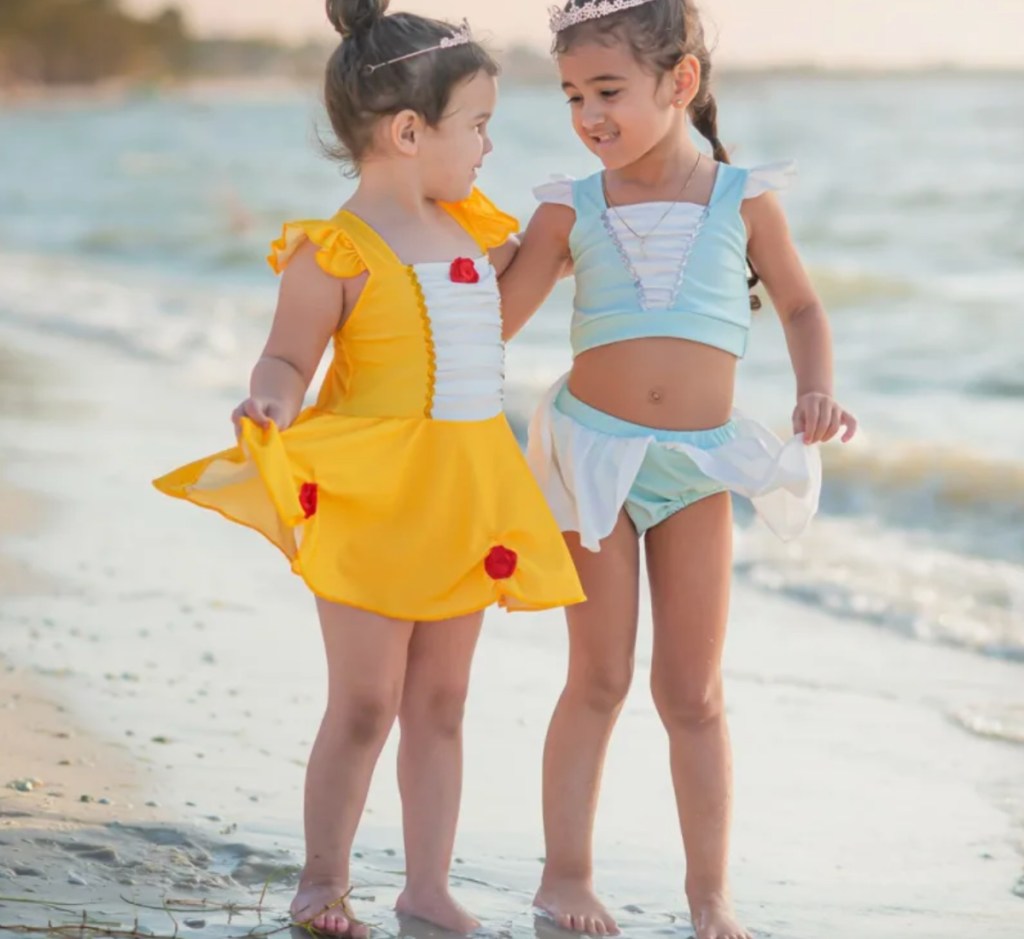 two girls in belle and elsa swimwear on beach