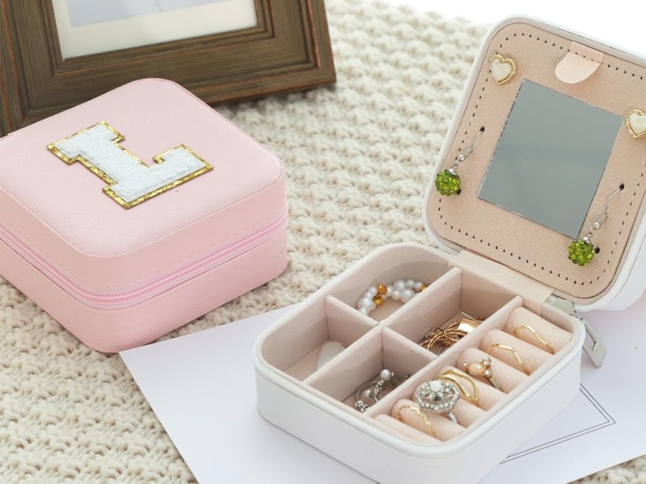 pink jewelry travel case with a block letter "L" Initial next to an open white case showing jewelry inside