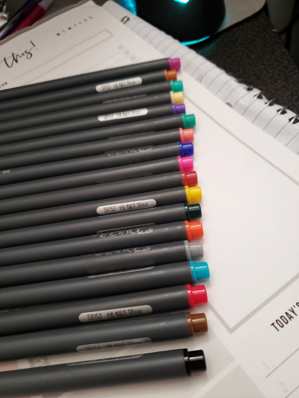 assorted journaling pens lined up against a notepad