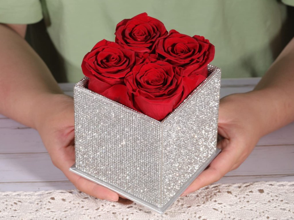 holding 4 red roses in a rhinestone box