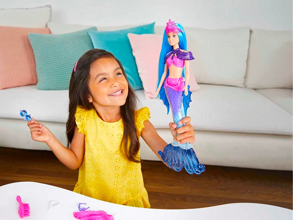 little girl playing with barbie mermaid doll 