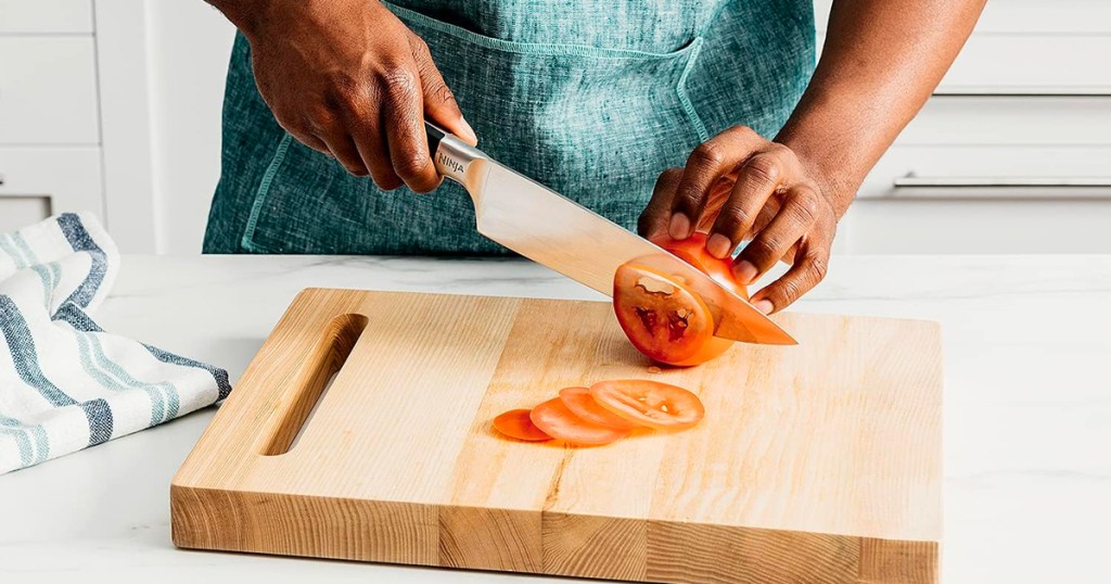 person cutting tomato with knife