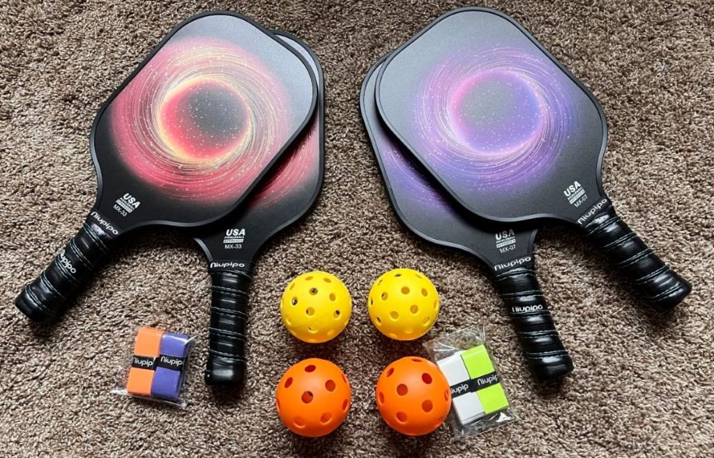 Four pickleball paddles, four pickleballs, and four tape grips
