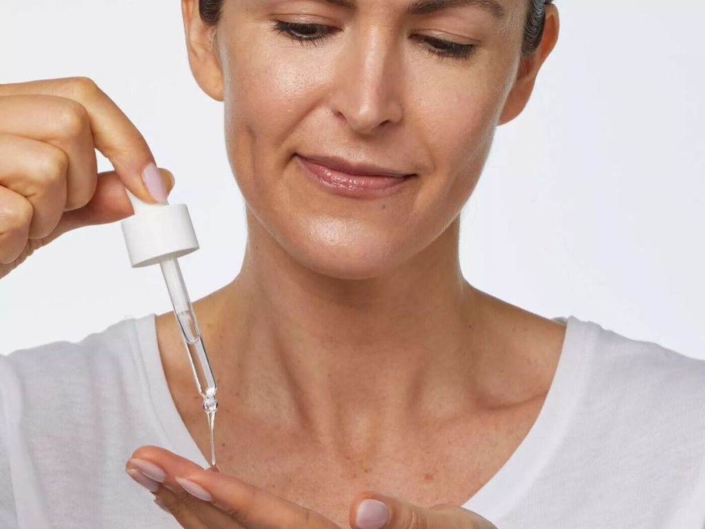 woman squeezing dropper of liquid onto finger