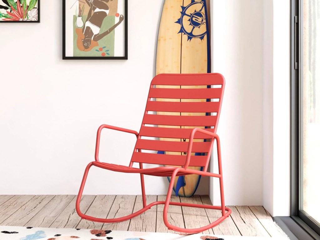 pink metal rocking chair sitting in front of surf board