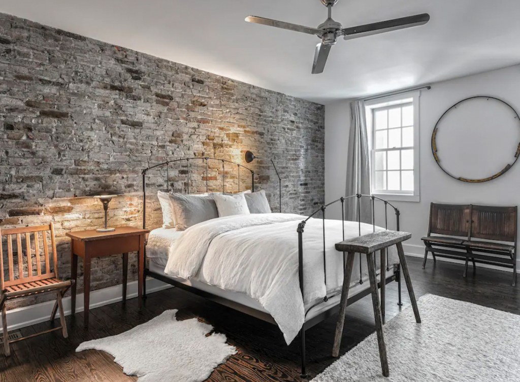 styled bedroom with brick wall and white bedding