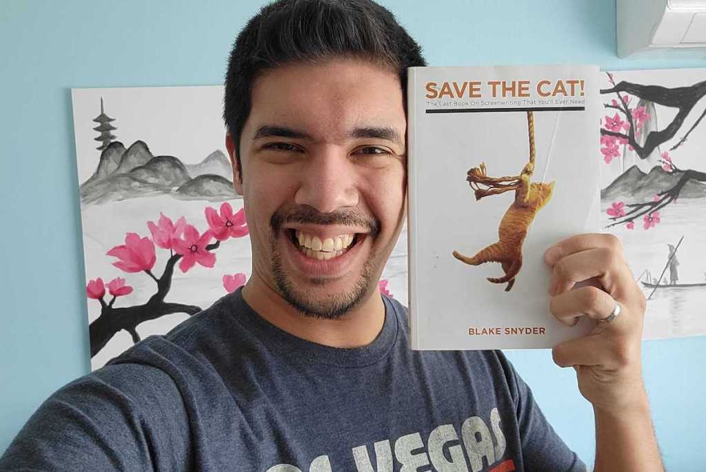 man holding save the cat book next to face
