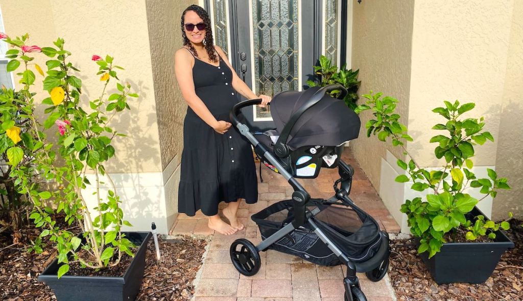 woman holding baby bump outside with stroller in front of home