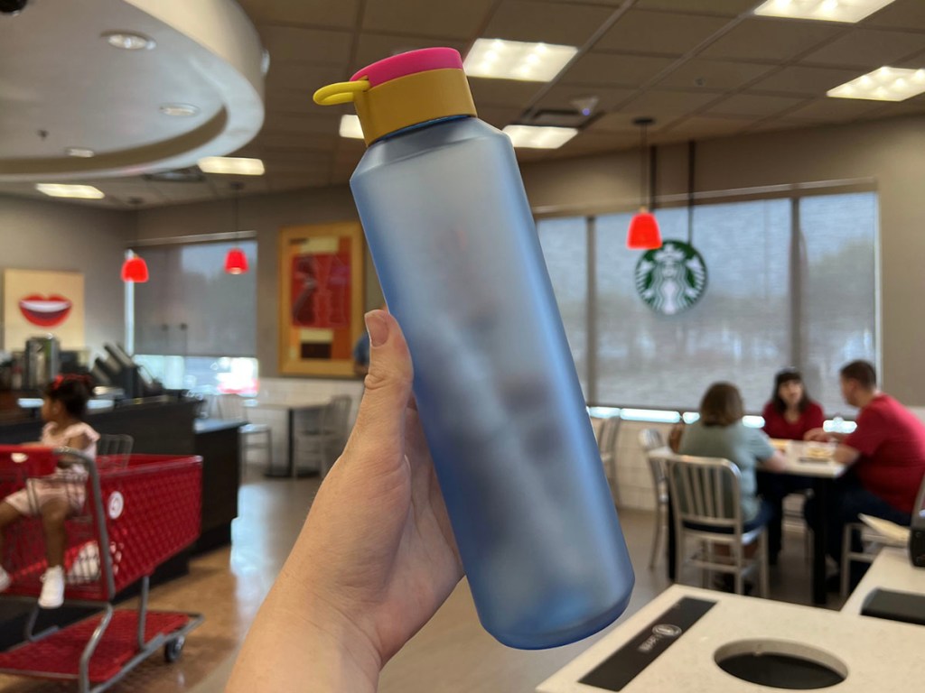 hand holding blue water bottle with yellow and pink top