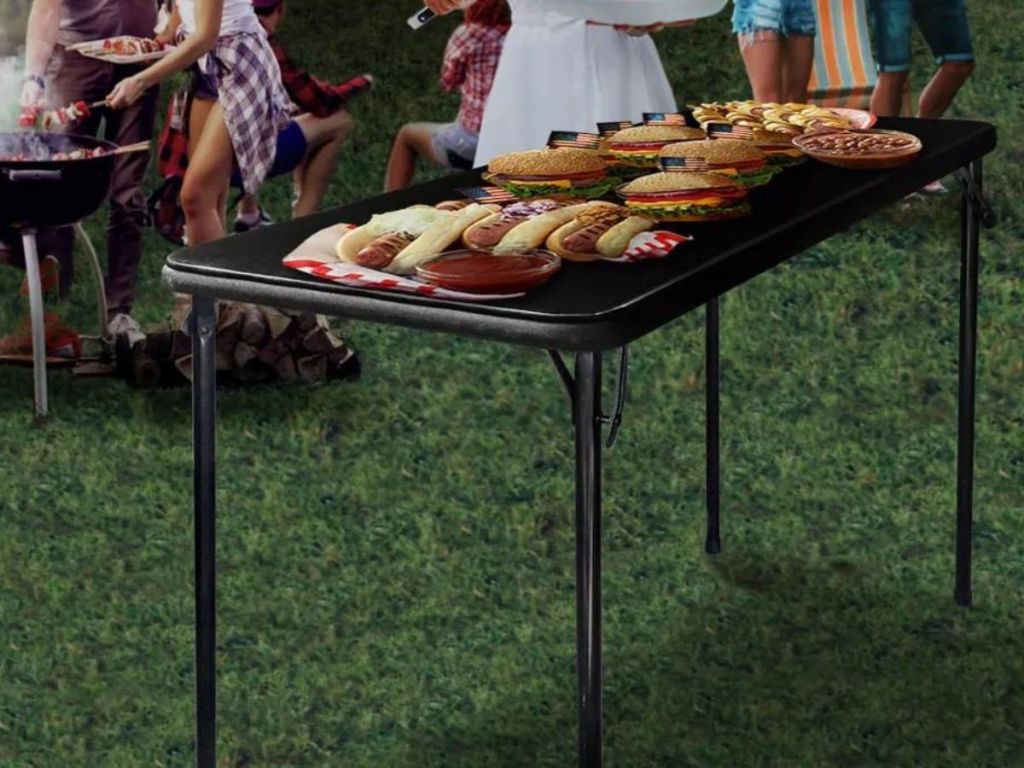 black folding table with hot dogs and hamburgers placed on top