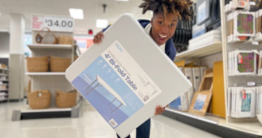 a woman holding a 4 ft folding table in a target store