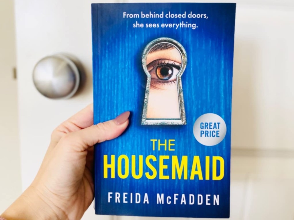 holding a paperback copy of The Housemaid