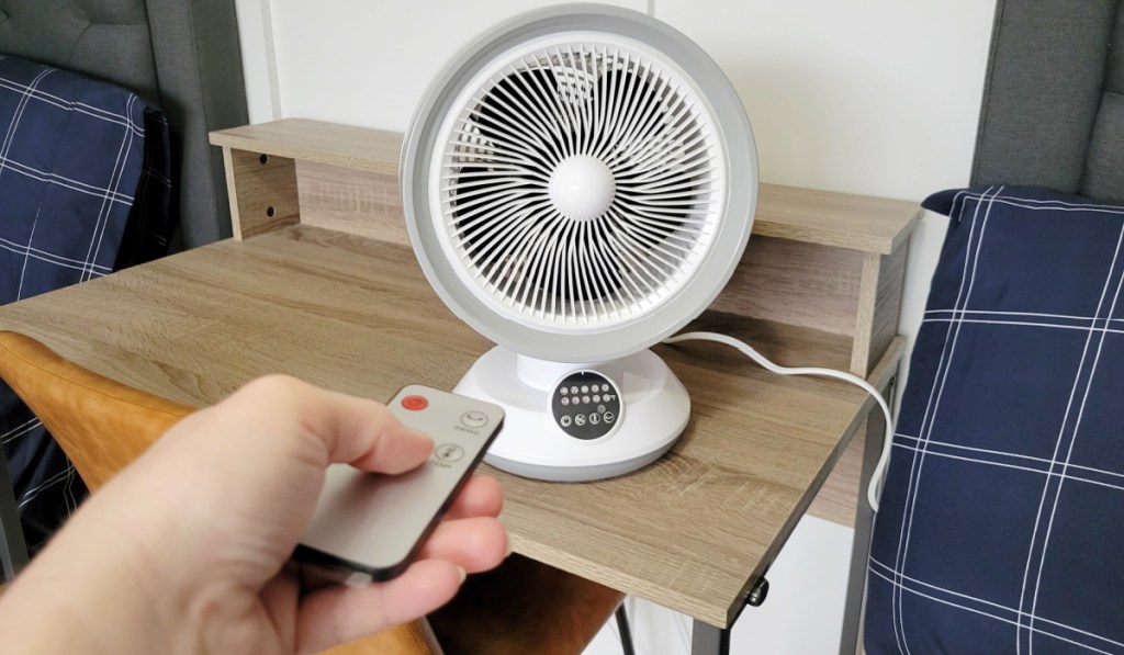 remote pointing at small round fan