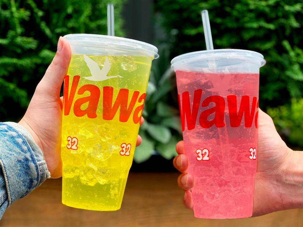 hands holding yellow and pink drinks