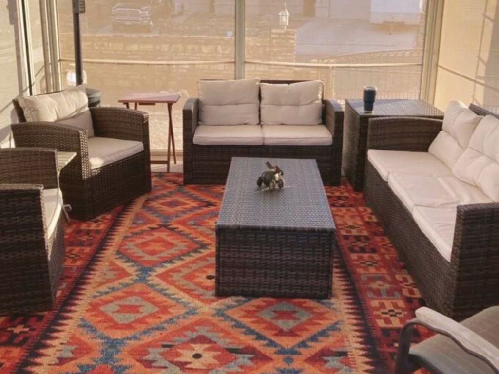Red/Yellow/Blue patterned area rug on porch with coffee table and furniture on it