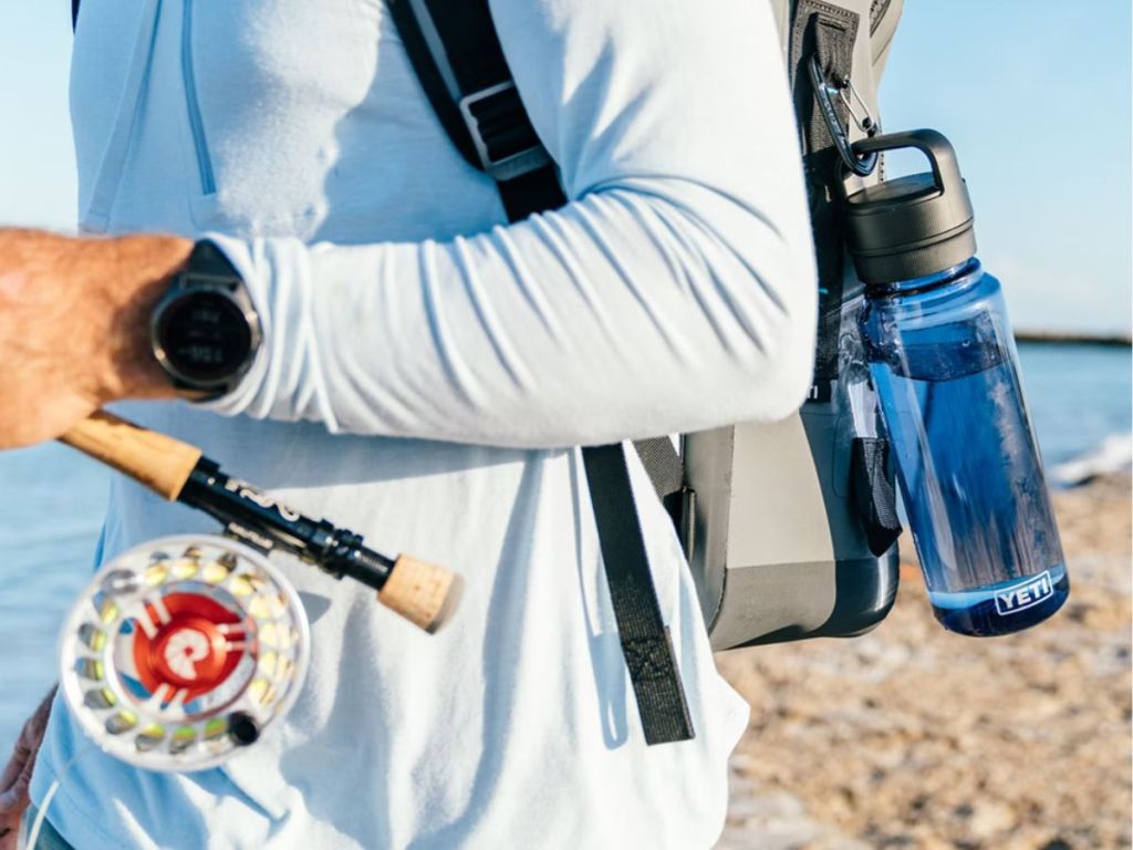 person with YETI Yonder water bottle clipped onto backpack