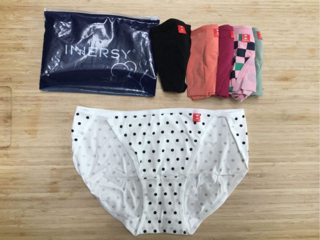 pair of white and black polka dot women's string bikini underwear with other pairs in different colors rolled up and the packaging that says "Innersy" above it
