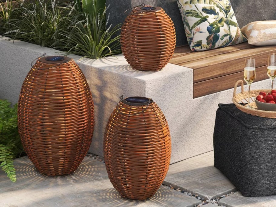 3 sizes of brown rattan wicker outdoor lanterns in an outdoor seating area