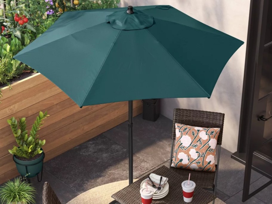 dark green patio table umbrella open above a table and chairs
