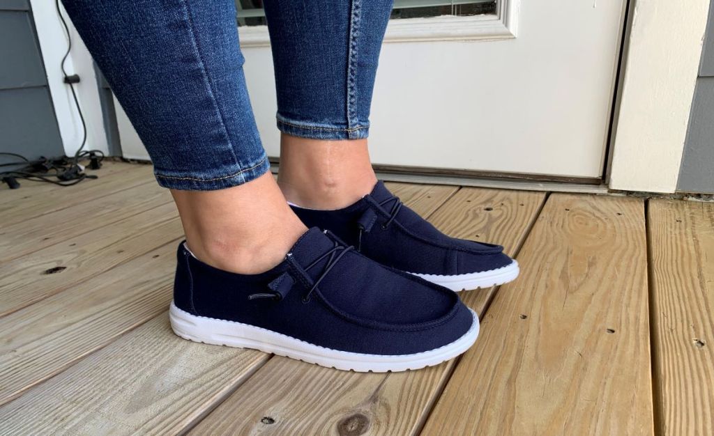 Person wearing a pair of navy blue canvas slip on shoes