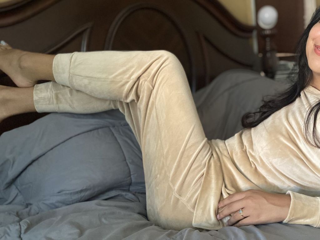 woman wearing tan velour leggings laying on bed